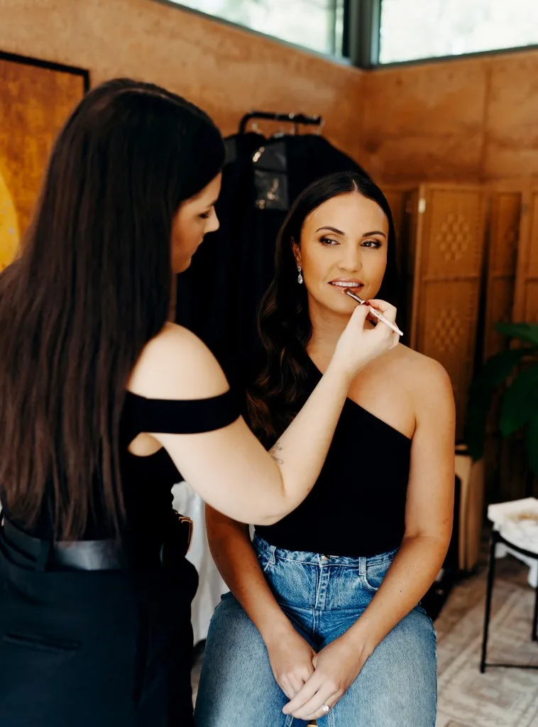 Makeup artist applying lip colour in a sunlit studio